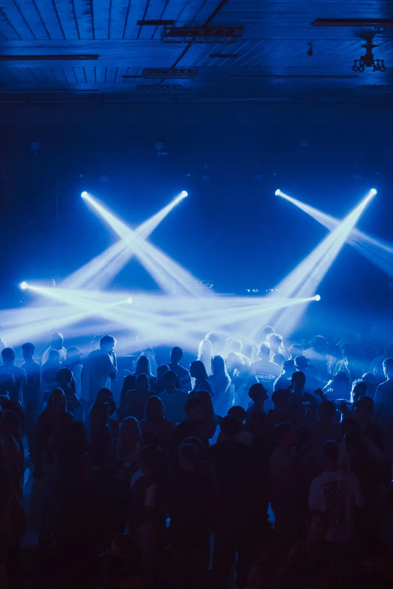 Sfeerbeeld: publiek onder blauwe lichtbundels tijdens een concert