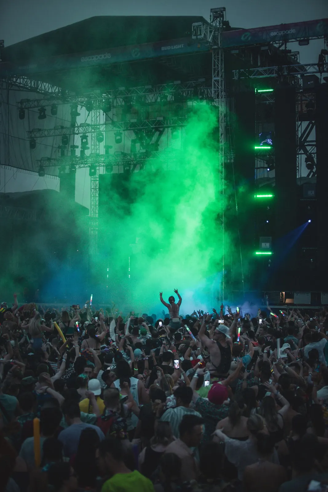 Sfeerbeeld: festivalpubliek 's avonds bij een podium met groen licht
